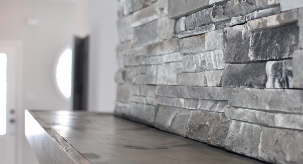 Close up shot of a wooden mantle against a grey stone fireplace in a new construction Lexington Ky home.