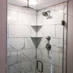 Marble tile shower with glass door and a rainfall showerhead.